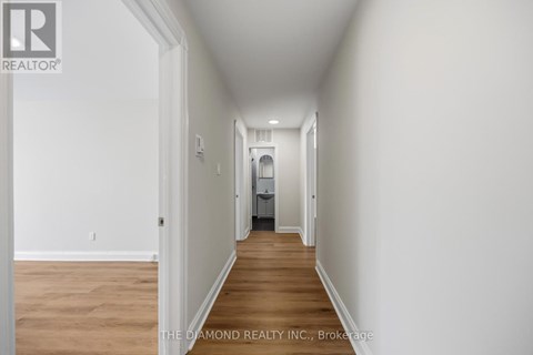 A long hallway with a door on the left and a bedroom at the end.