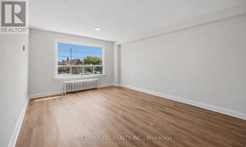 A room with a window showing a view of a house and trees.