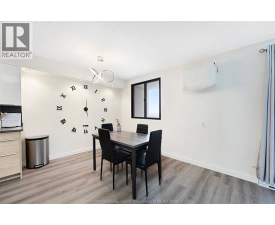 A dining room with a table set for two and a clock on the wall.