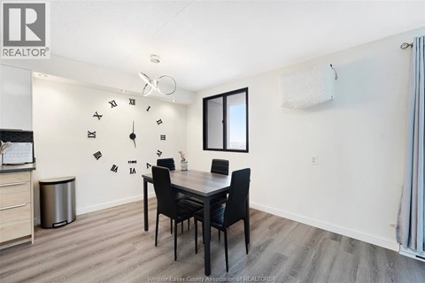 A dining room with a table set for two and a clock on the wall.