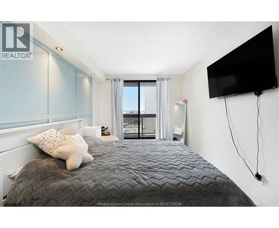 A bedroom with a large bed and a flat screen TV mounted on the wall.