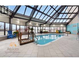 A large indoor swimming pool with a glass ceiling and a wooden staircase leading to it.