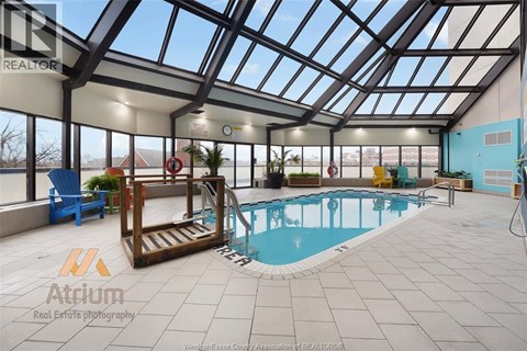 A large indoor swimming pool with a glass ceiling and a wooden staircase leading to it.