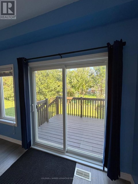 A sliding glass door with a view of a deck and trees outside.