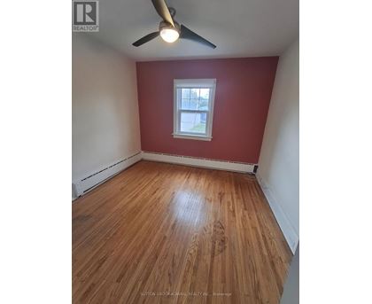 A room with a ceiling fan and wooden flooring.