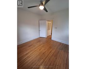 A room with a ceiling fan and wooden flooring.