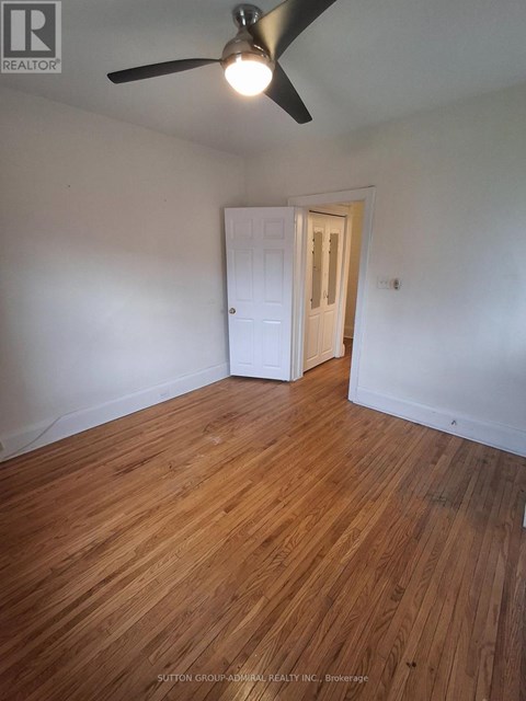 A room with a ceiling fan and wooden flooring.
