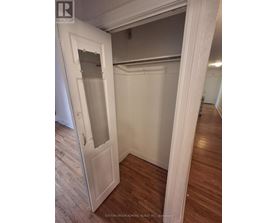 A white door with a glass window is open to a room with wood flooring.