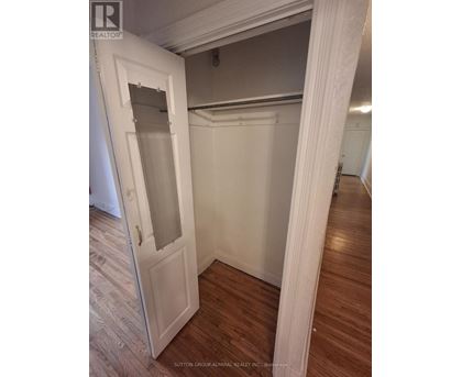 A white door with a glass window is open to a room with wood flooring.