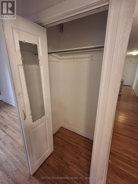 A white door with a glass window is open to a room with wood flooring.