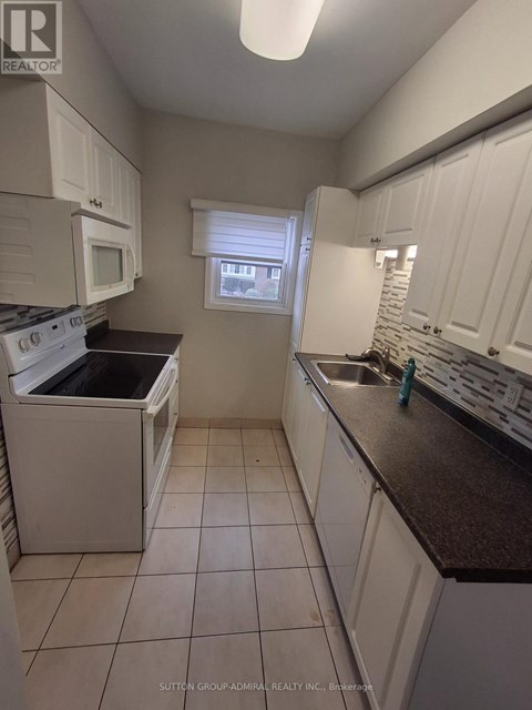 A kitchen with white cabinets and a black counter top.