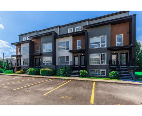 Apartment building with a parking lot in front.