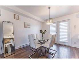 A dining room with a glass table and white chairs.