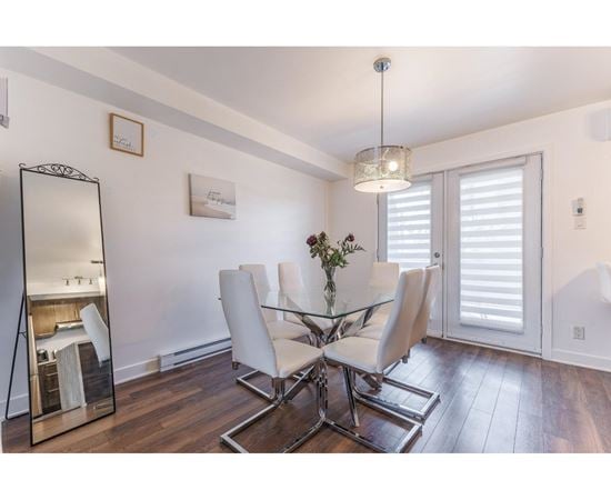 A dining room with a glass table and white chairs.