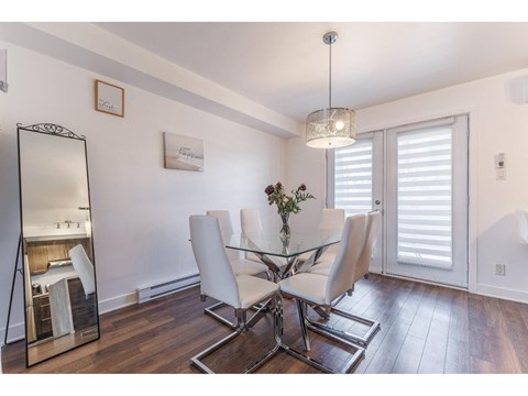 A dining room with a glass table and white chairs.