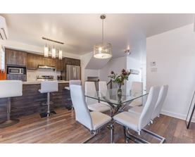 A modern kitchen with a glass table and white chairs.