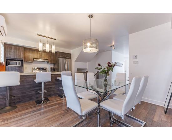 A modern kitchen with a glass table and white chairs.