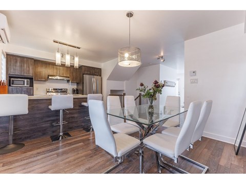 A modern kitchen with a glass table and white chairs.