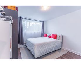 A bedroom with a white bed and grey curtains.