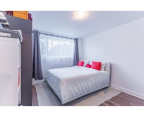 A bedroom with a white bed and grey curtains.