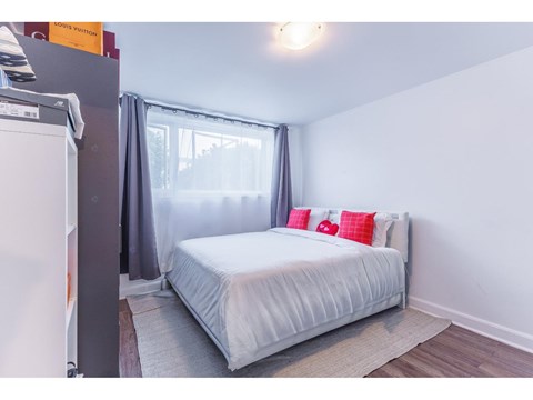 A bedroom with a white bed and grey curtains.