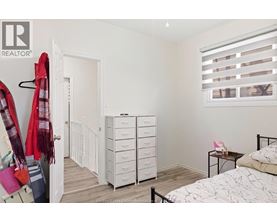A bedroom with a bed, dresser, and window with blinds.