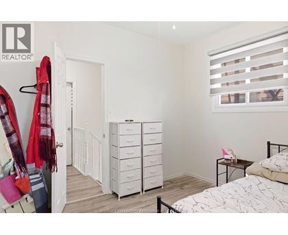A bedroom with a bed, dresser, and window with blinds.