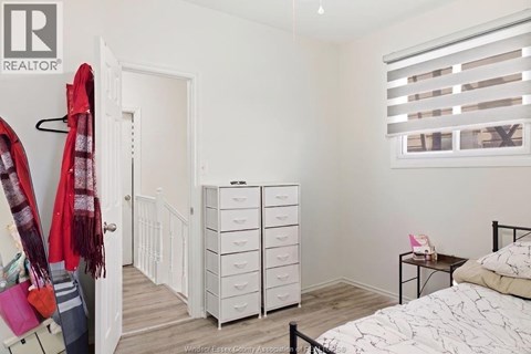 A bedroom with a bed, dresser, and window with blinds.