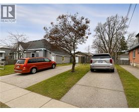A red van is parked in front of a grey house.