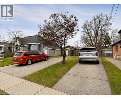 A red van is parked in front of a grey house.
