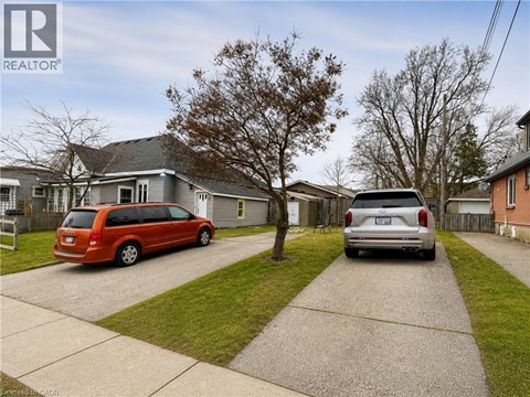 A red van is parked in front of a grey house.