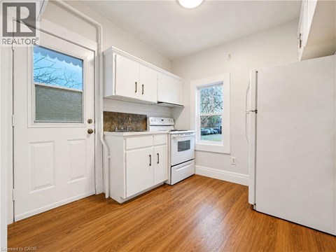 A kitchen with white cabinets and a wooden floor.