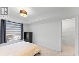 A bedroom with a large bed and a window with curtains.