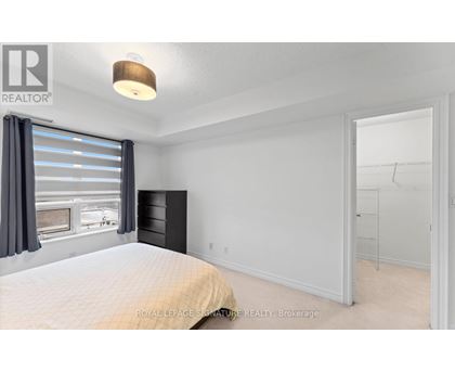 A bedroom with a large bed and a window with curtains.