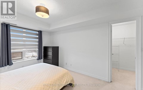 A bedroom with a large bed and a window with curtains.
