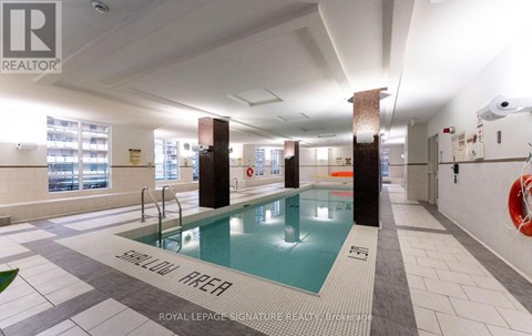 A swimming pool in a room with a sign that says "SHALLOW WATER".