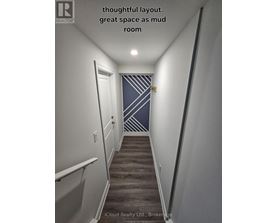 A hallway with a wooden floor and a striped wallpaper on the wall.