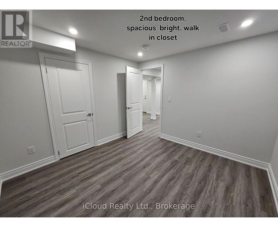 A second bedroom with wood flooring and white walls.