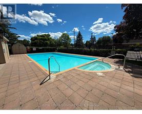 A pool surrounded by a brick patio and a black fence.