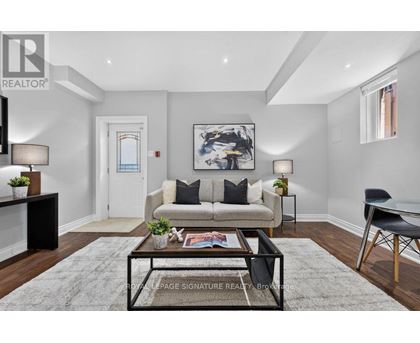 A living room with a couch, coffee table, and a painting on the wall.