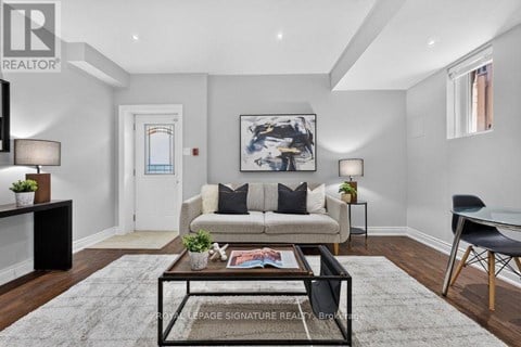 A living room with a couch, coffee table, and a painting on the wall.