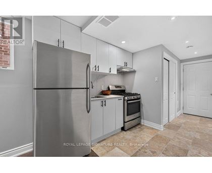 A kitchen with a stainless steel refrigerator and a tiled floor.