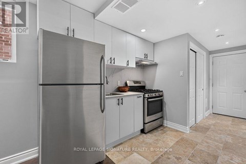 A kitchen with a stainless steel refrigerator and a tiled floor.