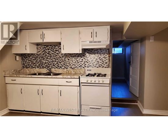 A kitchen with white cabinets and a black and white backsplash.