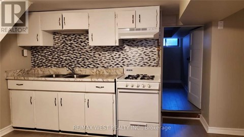 A kitchen with white cabinets and a black and white backsplash.