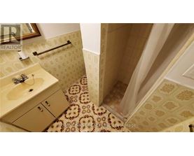 A bathroom with a tiled floor and a shower area.