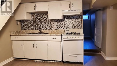 A kitchen with white cabinets and a black and white tiled backsplash.