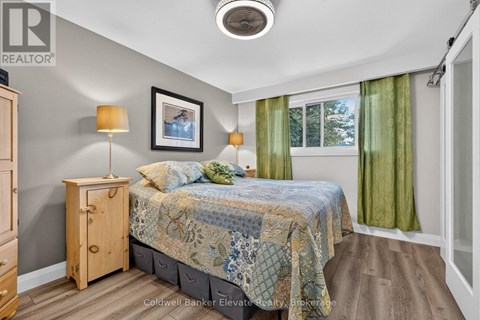 A bedroom with a bed, nightstand, and a window with green curtains.