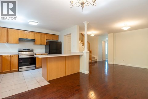 A well-lit kitchen with wooden cabinets and a black fridge.