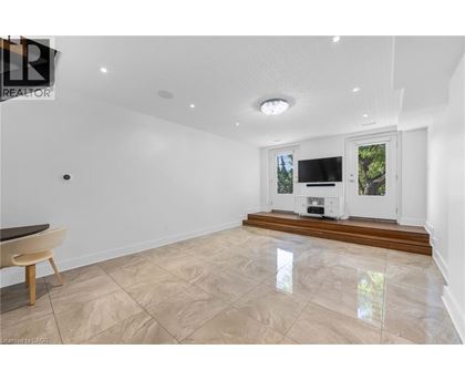 A spacious living room with a television and a window overlooking a tree.